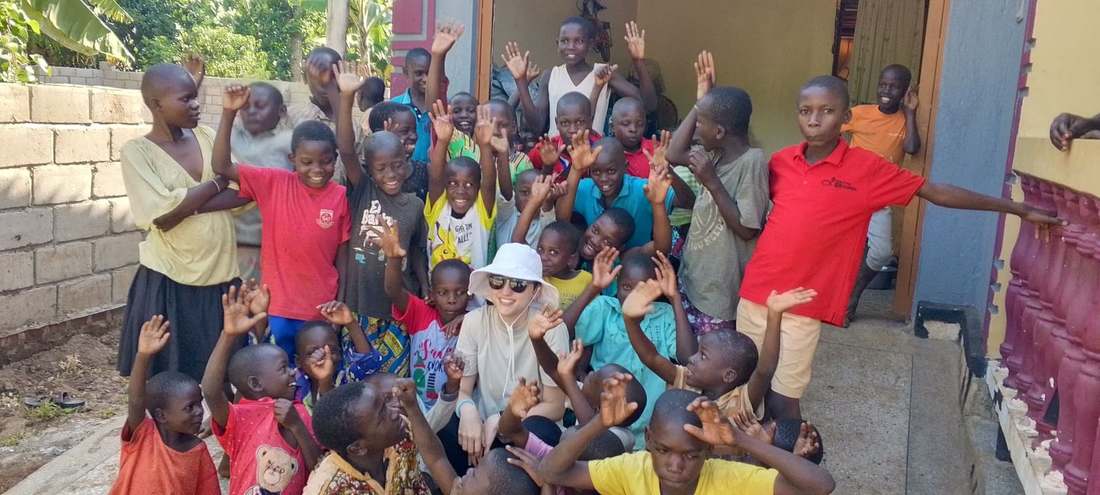 A large group of children waving with a volunteer